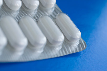 Part of a plate with pills on a blue background close-up and place for text