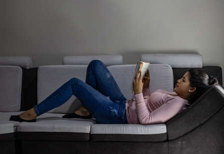 Young woman reading book on the sofa at homeの写真素材
