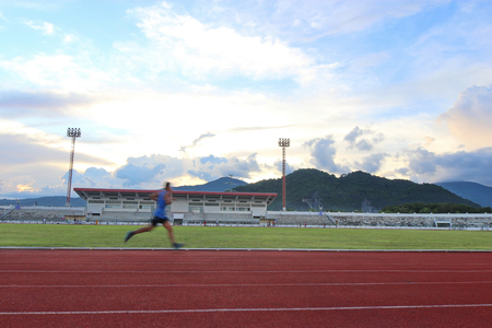 running in the stadium, mountain and blue sky backgroundの写真素材