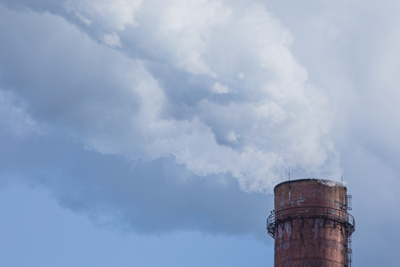 The steaming pipe of the plant or factory on the background of the blue sky.の写真素材