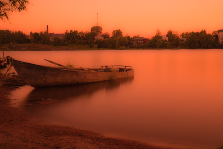 The boat is the shore of the river. The summer countryside in the warm orange colorsの写真素材