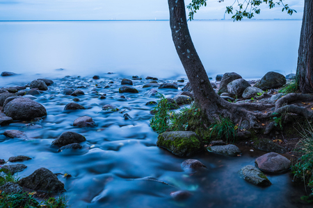 The water flow or stream running to the gulf of the sea among the rocks and stonesの写真素材
