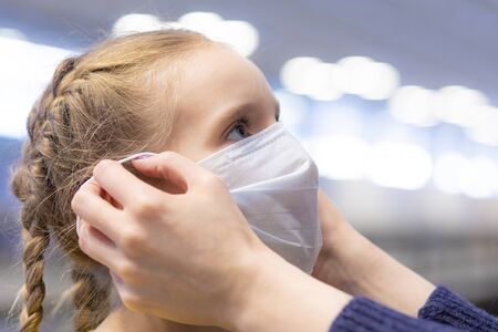 Mother hands dressing protection mask on girl