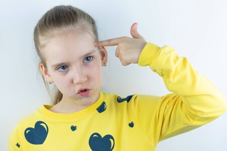 Girl in yellow sweater with forefinger near temple