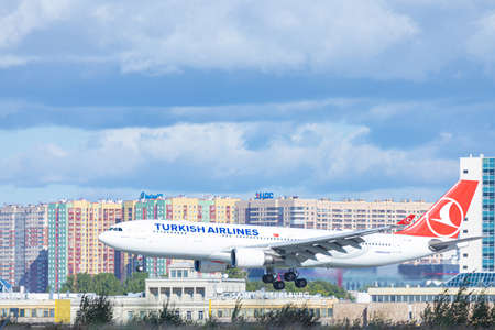 Pulkovo airport near Saint Petersburg / Russia - September 19 2020: Airplane of turkish airlines company with chassis from the side landing or taking off on background of buildings and blue cloudy skyのeditorial素材