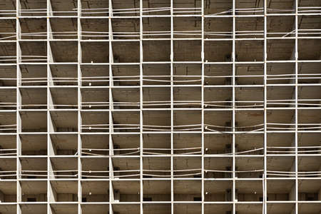 The light or bright gray urban background or backdrop of new concrete building construction in the rays of midday sun with many lines, squares and rectangles like grid, grid or grate structureの写真素材