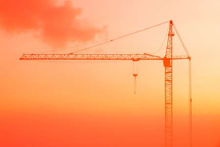Beautiful landscape or scene of silhouettes of building crane on the red, orange, scarlet or crimson background of sunrise or sunsetの写真素材