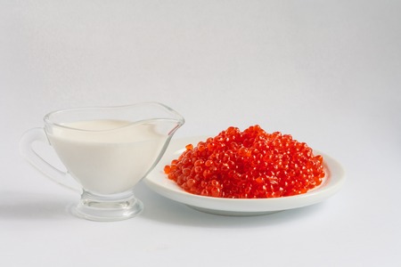 Red caviar on the plate on the white background and jug of milkの写真素材