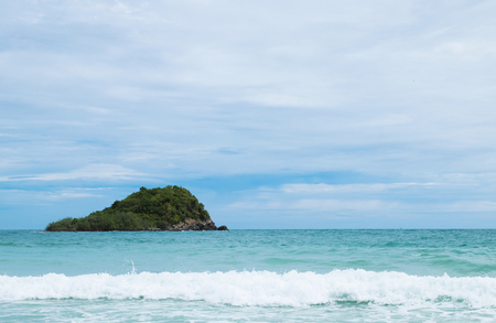 wave in the ocean with blue sky and green mountain backgroundの写真素材