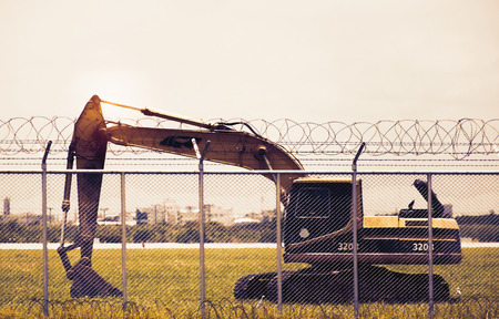 Backhoe is working on the grass field in the net fence.の写真素材
