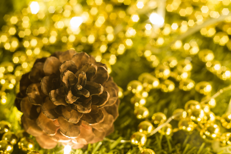 Soft focused on Pine cones surrounded by gold bead and Christmas party accessories on wooden tableの写真素材