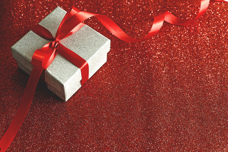 Glitter silver gift box with red ribbon on red glitter background,Valentines day celebration seasonal for loversの写真素材