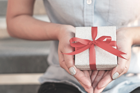 Womens in blue shirt hold gift box with red ribbon on her both hands,Gift for lover or important...