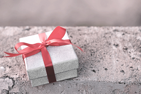 Glitter silver gift box with red ribbon on concrete backgroundの写真素材