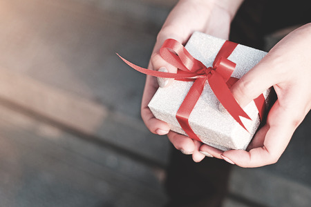 Woman's in blue shirt hold gift box with red ribbon on her both handsの写真素材