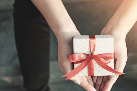Womens in blue shirt hold gift box with red ribbon on her both hands,Gift for lover or important personの写真素材