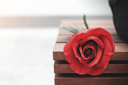 The roses were place beside that girl sitting waiting for someone at the Brown wooden chairs.の写真素材