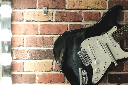 Black guitar hang on the brick wall