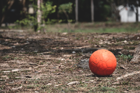 Old orange ball place on dry grass field with nobody play.の写真素材