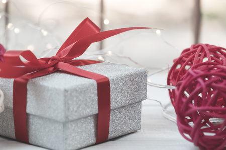 Glitter silver gift box and decorated ball on white wooden background.の写真素材