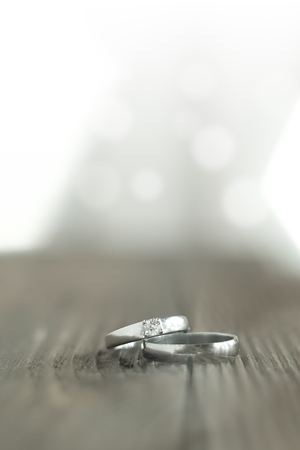 Two wedding rings place on wooden floor with light bokeh background.の写真素材