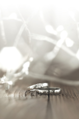 Two wedding rings place on wooden floor with light bokeh background.の写真素材