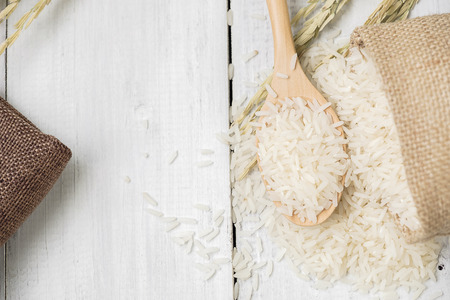 A wooden spoon filled with rice placed on wooden background.の写真素材