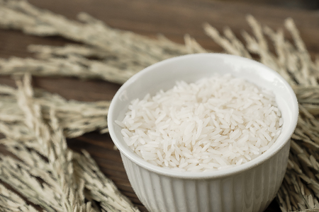 Rice in white bowl on yellow rice plant background.の写真素材