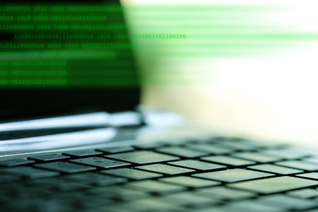Computer source code on laptop keyboard and blank monitor background