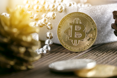 Golden bitcoin placed near gift box and pine coneの写真素材