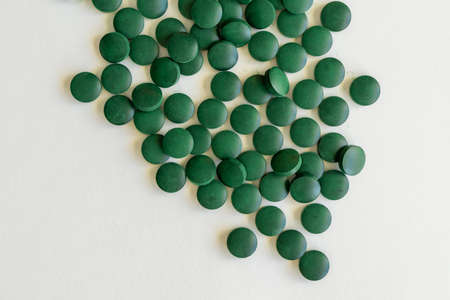 Some Spirulina supplements round green pills on a white background. Top view of Chlorella tablets are food supplements.の写真素材