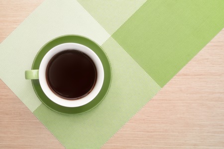 Green cup of coffee on the background of the pink wood table and tablecloth. View from topの写真素材