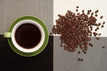 Green cup of coffee on black and white tablecloth background and scattered coffee beans. Office, classic strict styleの写真素材