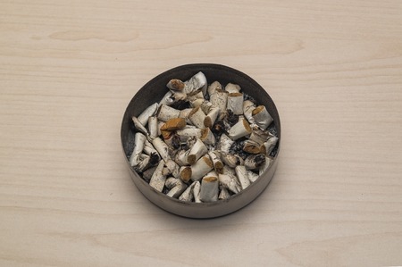 Ashtray and cigarette butts against the background of a light tableの写真素材