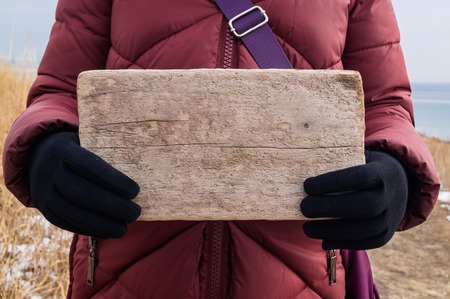 Wooden sign or board in female hands as a layout for the message textの写真素材