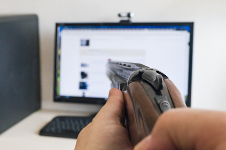 The concept of hatred of the computer and modern technologies presented as the aiming of a hunting or sporting classic smoothbore shotgun for shotの写真素材