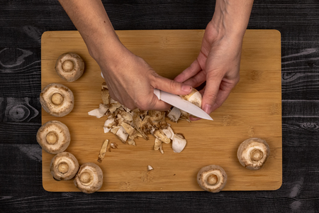Cleaning and slicing mushrooms as part of the process of preparing fresh champignons for freezingの写真素材