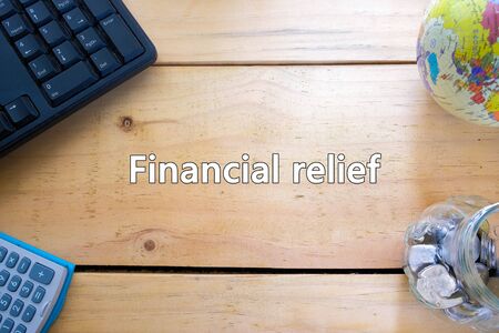 Conceptual government economic stimulus packages in financial relief during crisis or Covid-19. Top view keyboard, calculator, texts, coins in jar and globe. Focus on wooden table.の写真素材