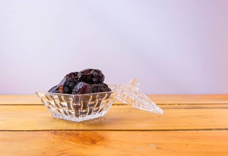 Side view of dates on glassware on wooden table. High in natural sugar packed with plenty of nutrients. Conceptual of breaking fast in ramadhan.の写真素材
