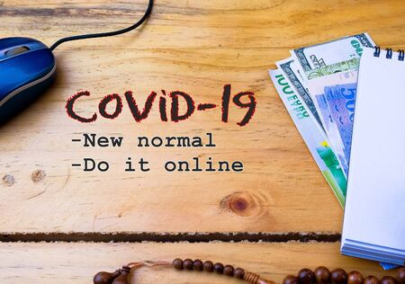 Texts zakat online (alms-giving) on wooden table during covid-19 lockdown. Conceptual.Obligation to aid the poors. Calculator, mouse and note book with texts on white. Selective focus.の写真素材