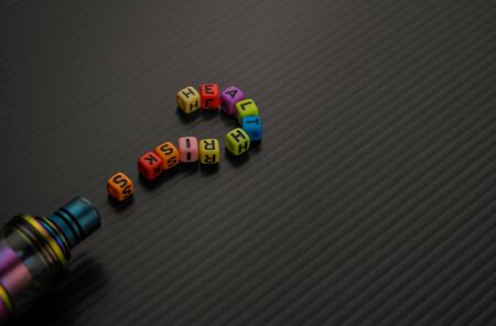 Conceptual of UNCERTAINTY of health safety of vaping or e-cigarette. Selective focus. Alphabet beads in question mark shape.の写真素材