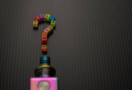 Alphabet beads UNCERTAINTY of health safety of vaping or e-cigarette. Selective focus. Conceptual