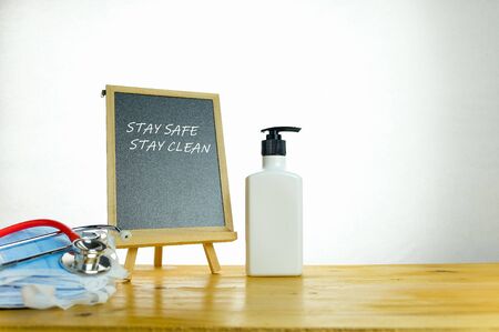 Conceptual of staying hygienic during coronavirus outbreak. Hand sanitizer and chalkboard isolated on wooden table. Focus on chalkboard only.の写真素材