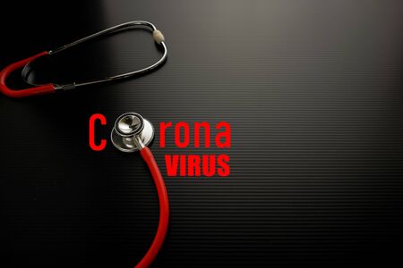 Conceptual image of corona virus outbreak originated from Wuhan China. Red stethoscope on dark surface with red texts Copy space. Focus on bell and diaphragm.の写真素材