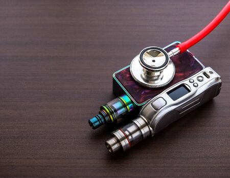 Conceptual image of uncertainty of health safety of e-cigarettes. Isolated close-up red stethoscope...