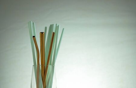 Conceptual of world issue on single use plastic against reusable steel straw. Steel straws in empty glass on reflective table.Selective focus at straws at center. Plastic straws in visibility.の写真素材