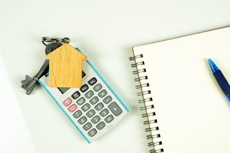 Conceptual image of debt service ratio for home loan repayment appraisal. Wooden key chain calculator notepad and pen in visibility. Focus on keychain.の写真素材