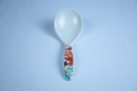 Plastic spoon on a blue background with a pattern of flowers., top viewの写真素材