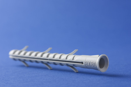 Plastic straddling dowel or rawl plug on a blue background