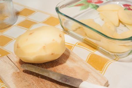 Potato and kitchen knife on a wooden cutting boardの写真素材